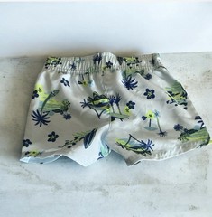 Light blue swim shorts with tropical print and elastic waist